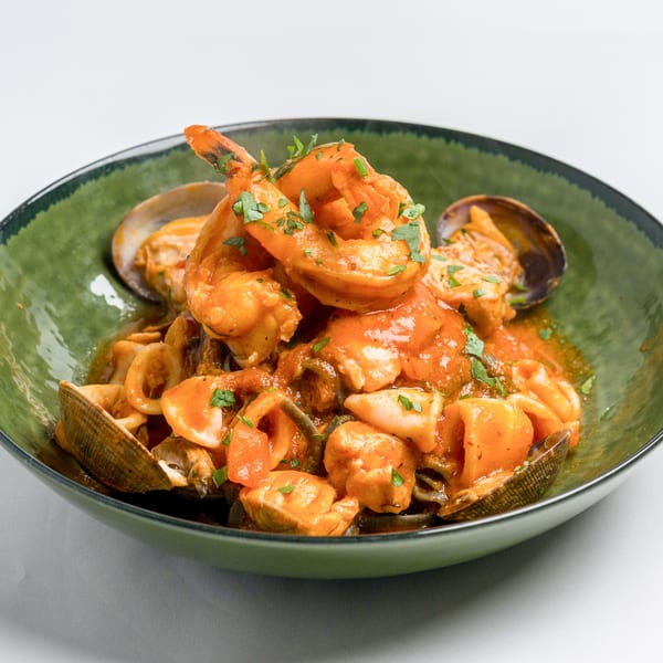 Seafood pasta with shrimp, clams, and calamari in a rich red sauce, garnished with parsley.